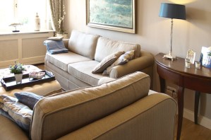 Ferienwohnung Zauberhaft - Einblick ins Wohnzimmer mit englischer Einrichtung, Sofa und Sessel mit Blick zum Fenster